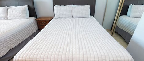 Ein Hotelzimmer mit einem großen Bett, zwei Nachttischen und einem Spiegel.