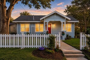 A single-story house with a red door, white picket fence, and a well-maintained lawn. - Historic Charm, Modern Comfort, Close to Downtown (Brenham)