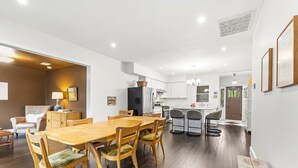 Een moderne keuken met witte kasten, een centraal eiland en een eetgedeelte met houten meubels.