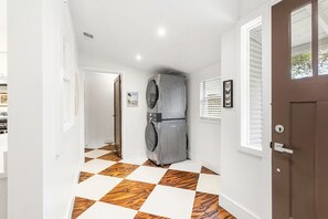 A hallway with a checkered floor, a door with a window, and a wall-mounted appliance. - Historic Charm, Modern Comfort, Close to Downtown (Brenham)