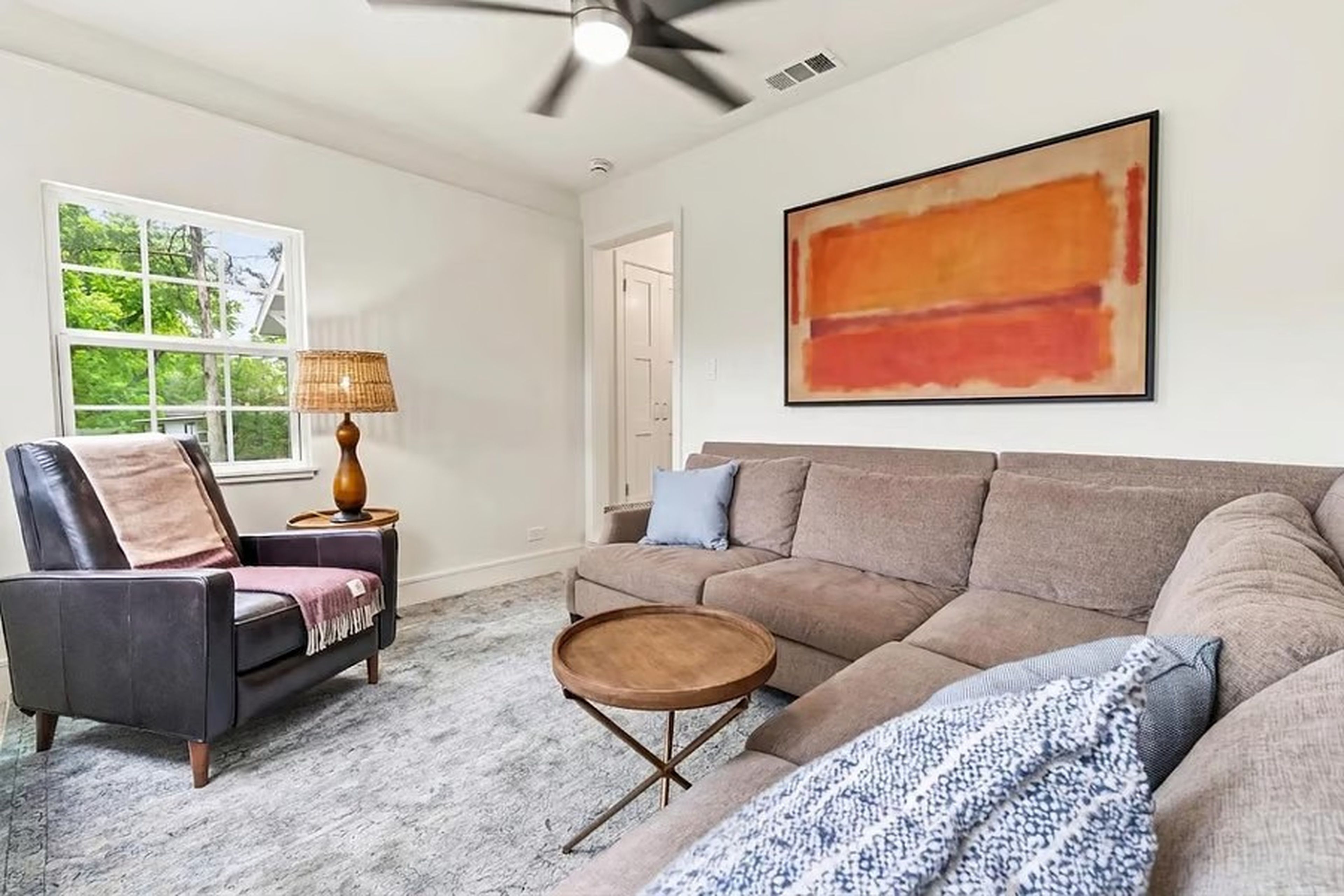 A living room with a sofa, armchair, coffee table, and a painting on the wall.