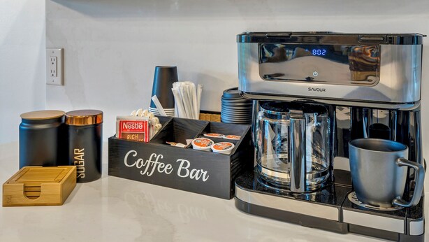 Eine Küche mit einer Kaffeebar, Regalen mit Tassen und einer Kaffeemaschine.