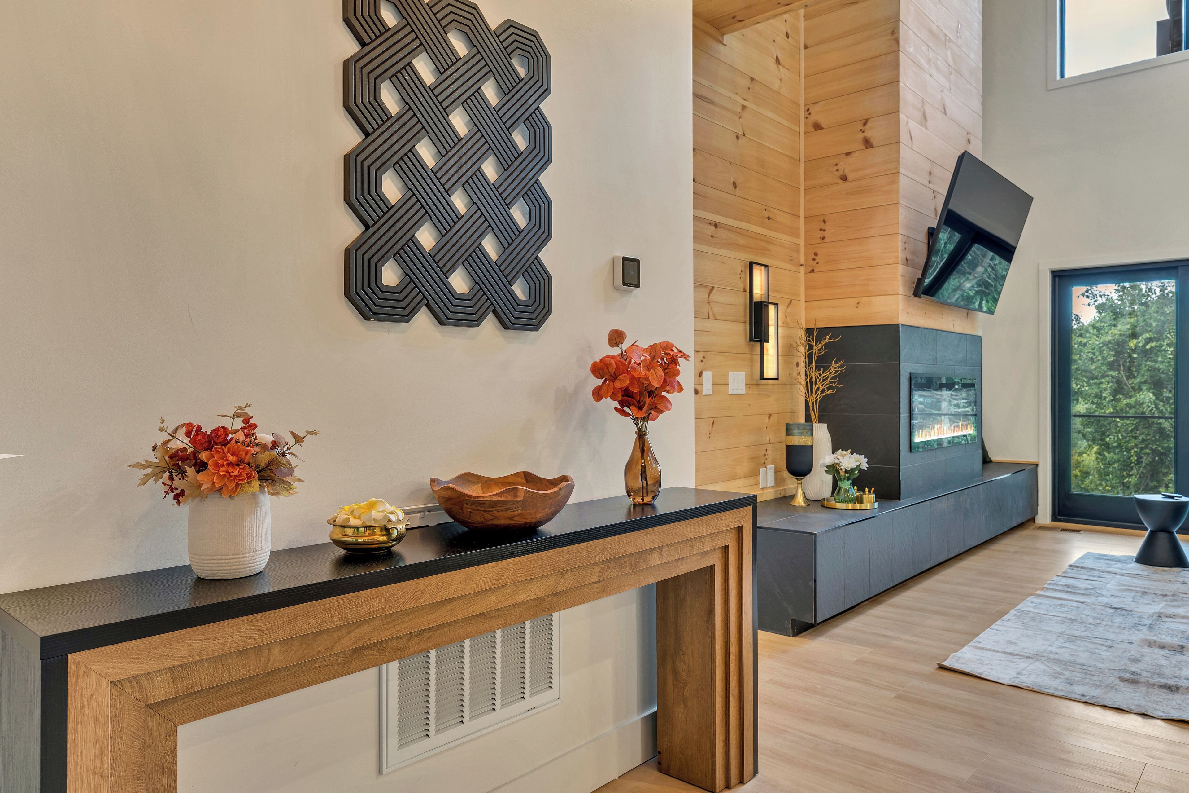 A modern interior with a wooden console table, decorative wall art, and a fireplace.