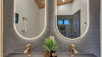 Une salle de bain avec deux lavabos, un grand miroir et une douche.