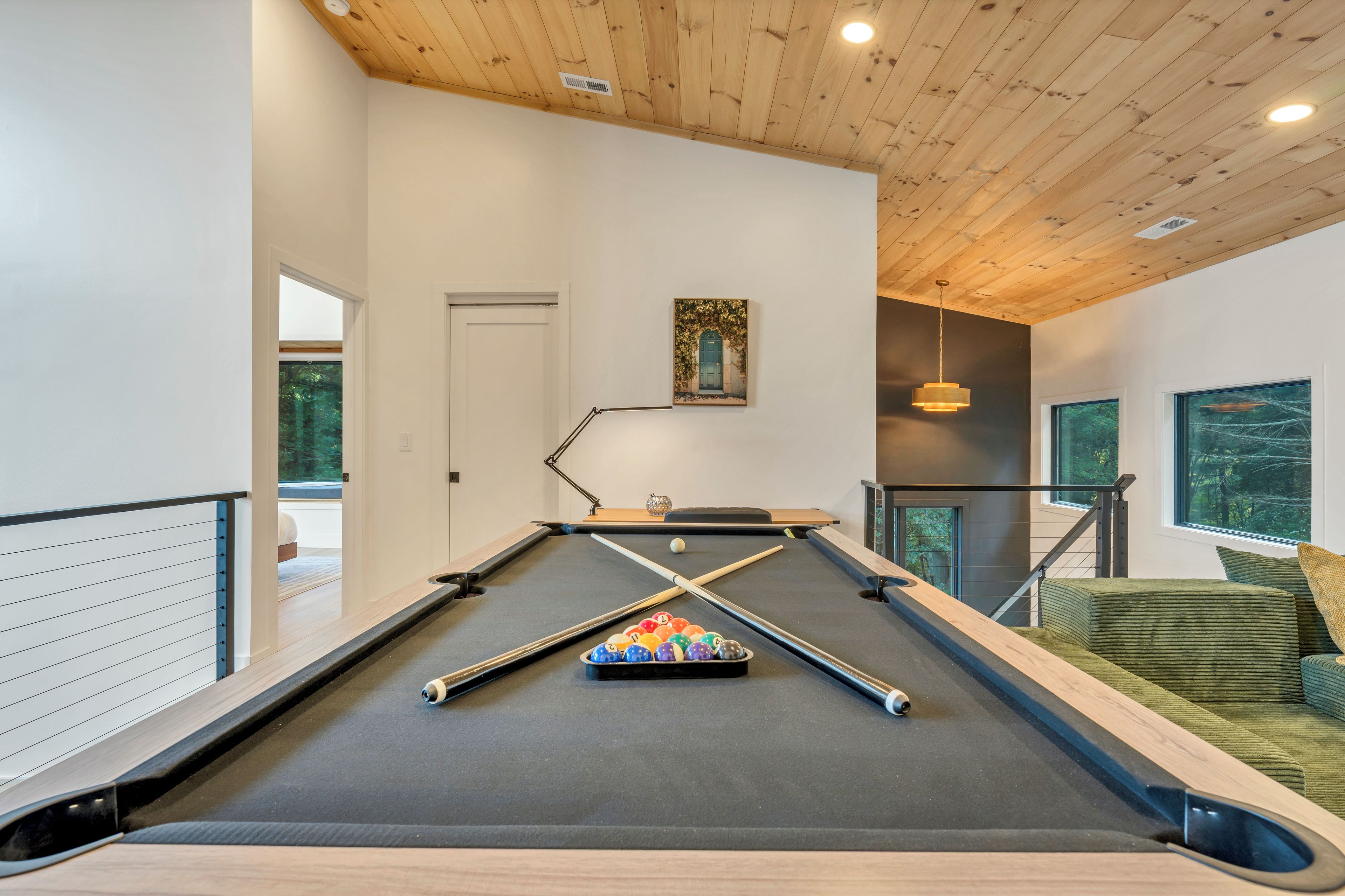 A pool table with a set of balls, a lamp, and a painting on the wall.