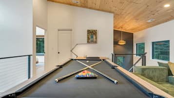 A pool table with a set of balls, a lamp, and a painting on the wall.