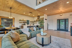 A modern living space with a wooden ceiling, a dining area, a kitchen, and a large window. - New Luxury Cabin - HotTub & Views - 5 min to Boone (Blowing Rock)