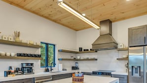 Eine moderne Küche mit einer zentralen Kochinsel, Barhocker und einem Edelstahl-Kühlschrank.