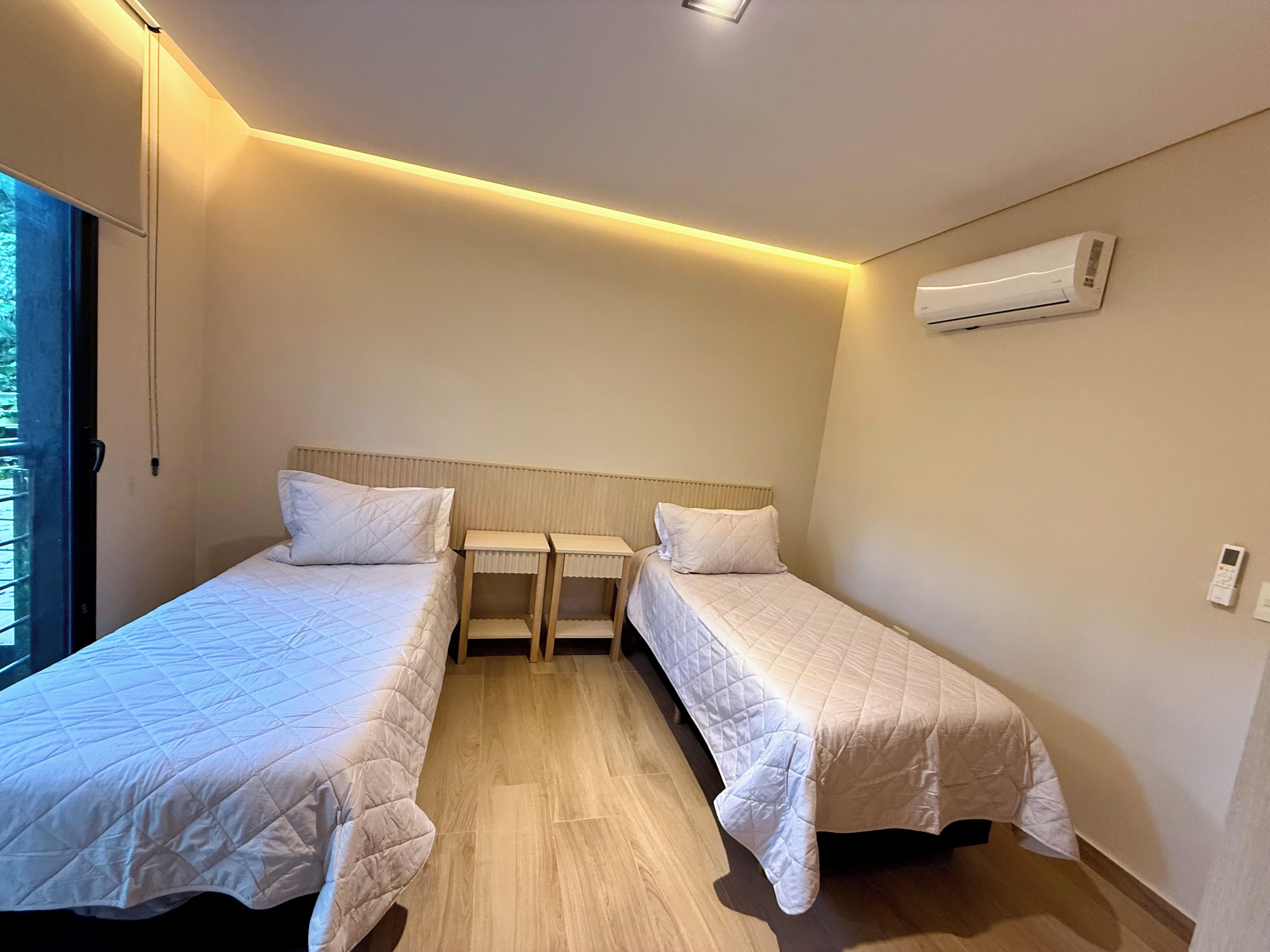 Une chambre d’hôtel avec deux lits, un luminaire au plafond, un climatiseur et une fenêtre.