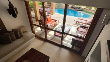 Un soggiorno moderno con divano, tavolino da caffè e vista su un’area piscina esterna.