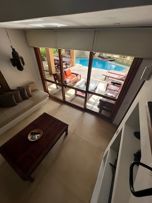 Una sala moderna con un sofá, una mesa de centro y vistas a un área de piscina al aire libre.