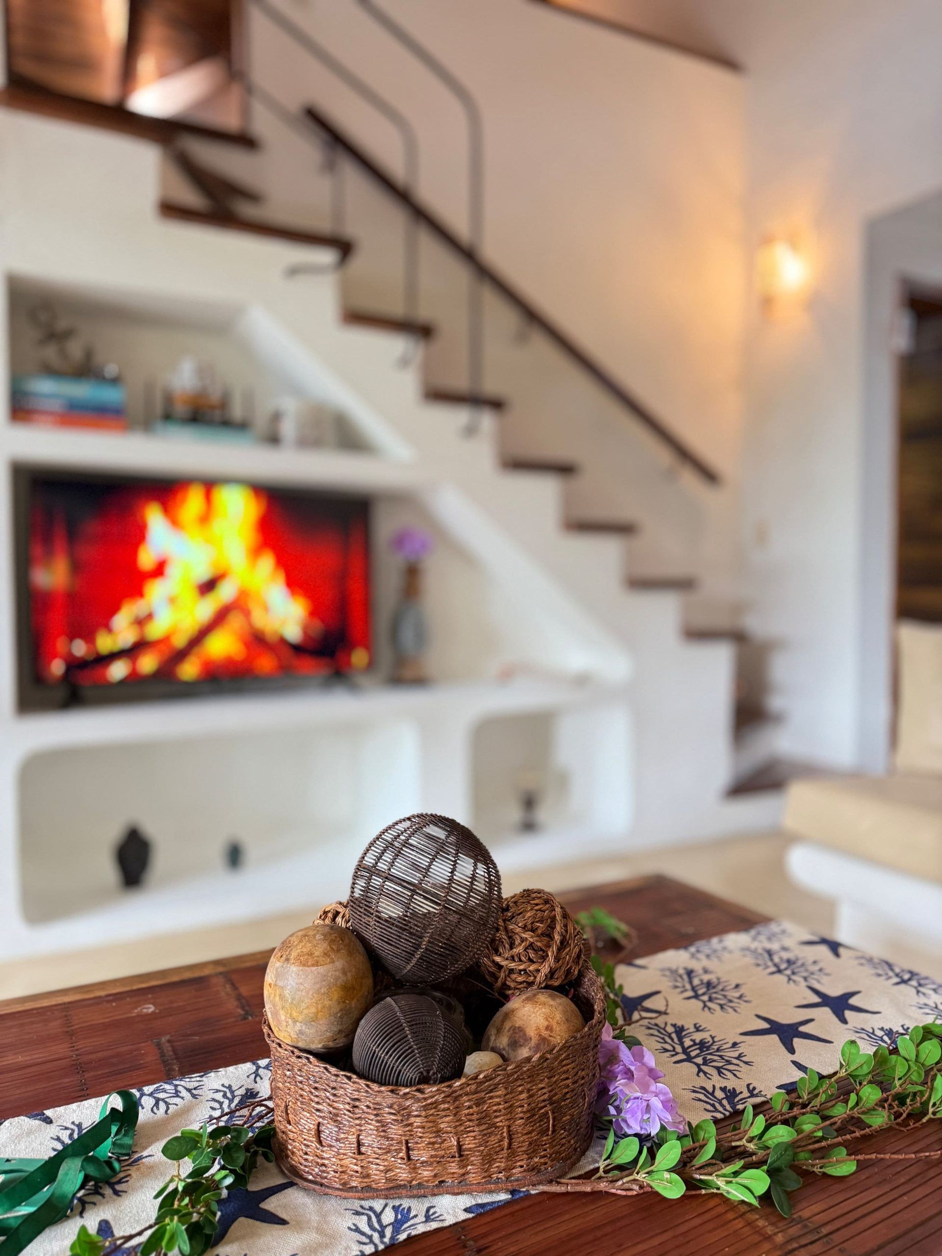 Un salon chaleureux avec une cheminée, un escalier et un panier décoratif pos é sur une table en bois.