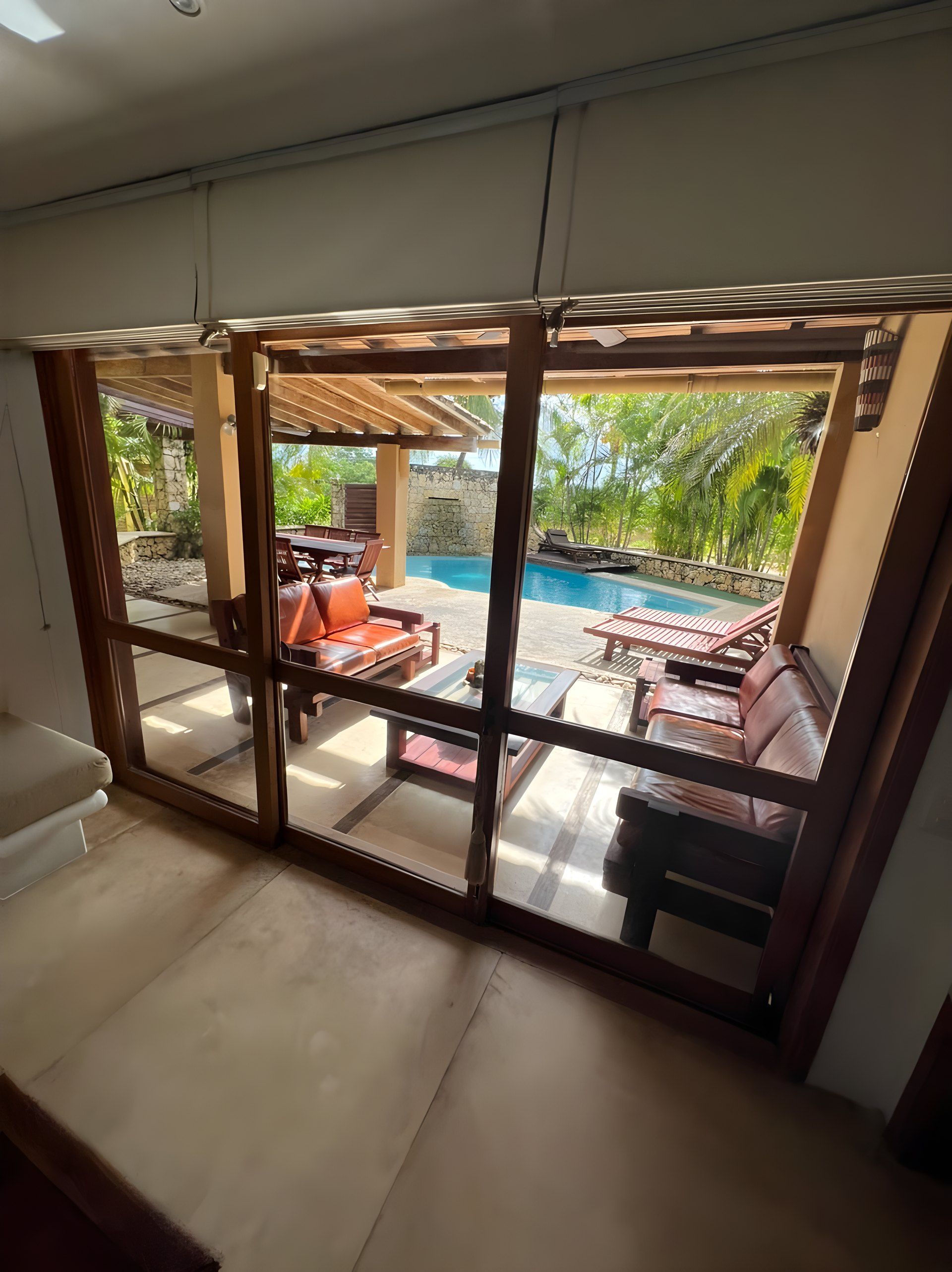 Una stanza con un'ampia porta vetrata che si apre su una zona esterna con piscina e lettini.