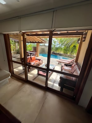 Una habitación con un amplio ventanal que da a un espacio exterior con piscina y sillones de descanso.