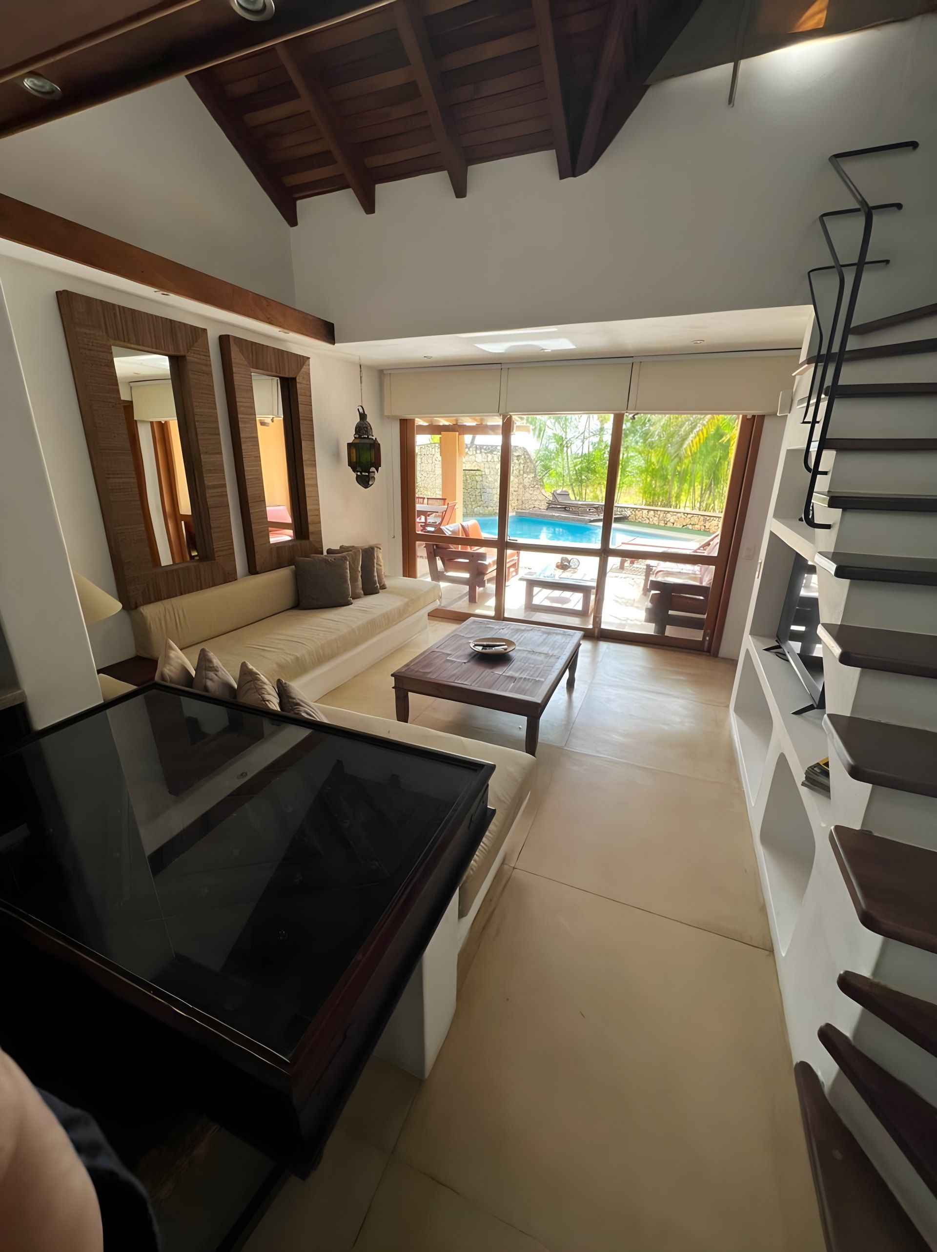 A modern living room with a pool view, a sofa, a coffee table, and a TV.