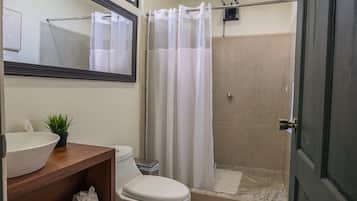 A bathroom with a toilet, sink, and shower area.