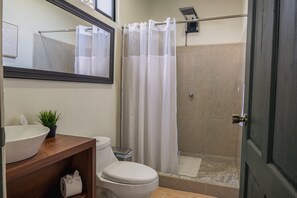 Un baño con inodoro, lavamanos y zona de ducha.