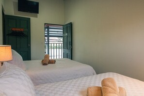 Habitación de hotel con dos camas, un televisor en la pared y vistas al exterior a través de una puerta.