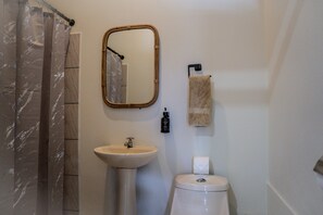 A bathroom with a shower curtain, a sink, a mirror, a towel rack, and a toilet. - Hotel Monteriggioni (Florencia)