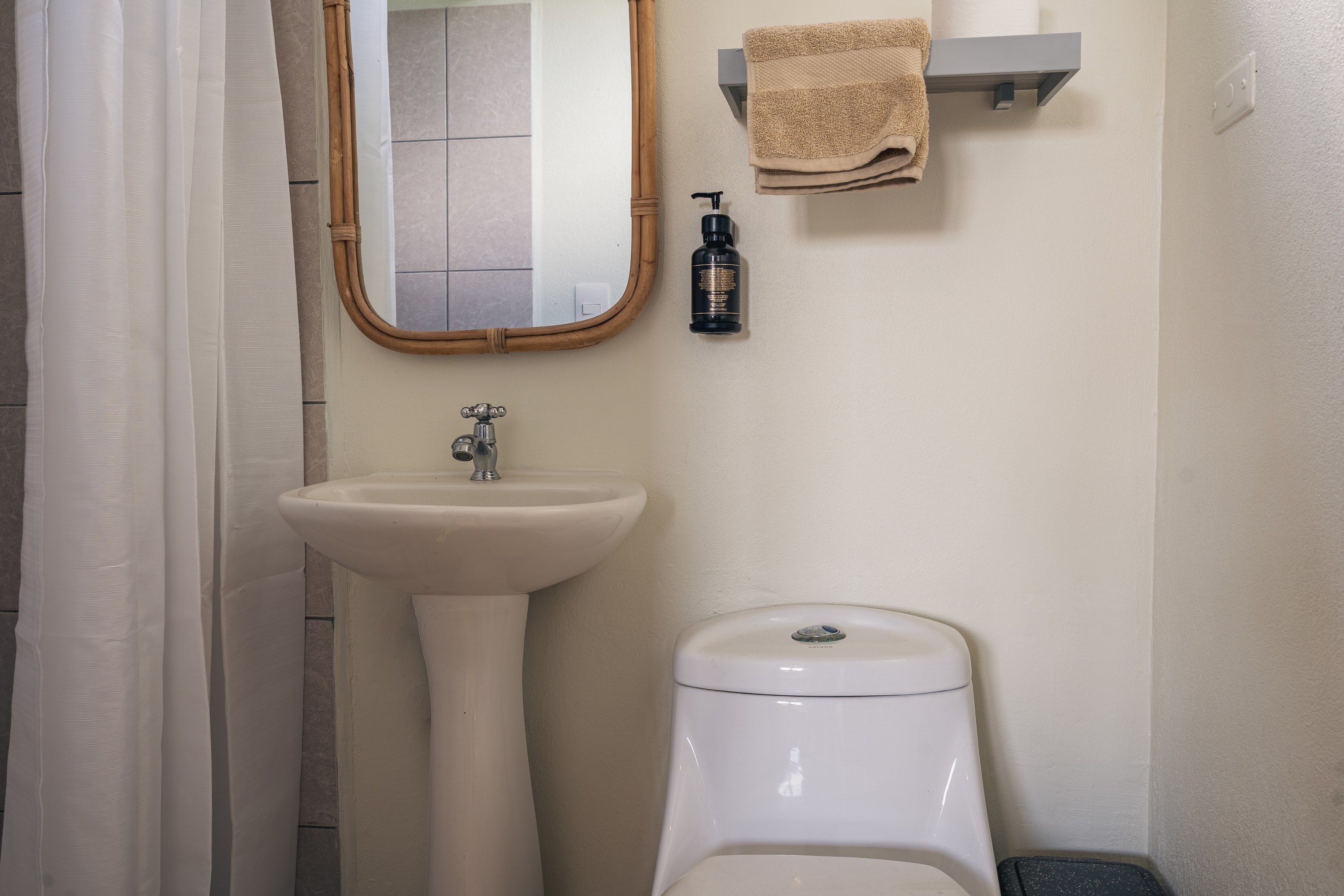 Un baño con lavamanos pedestal, inodoro, espejo y perchero para toallas.