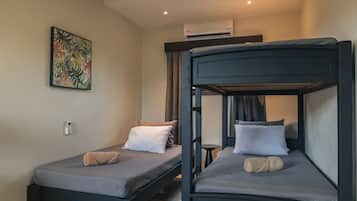 A room with two bunk beds, a small table, a wall-mounted air conditioner, and a painting.