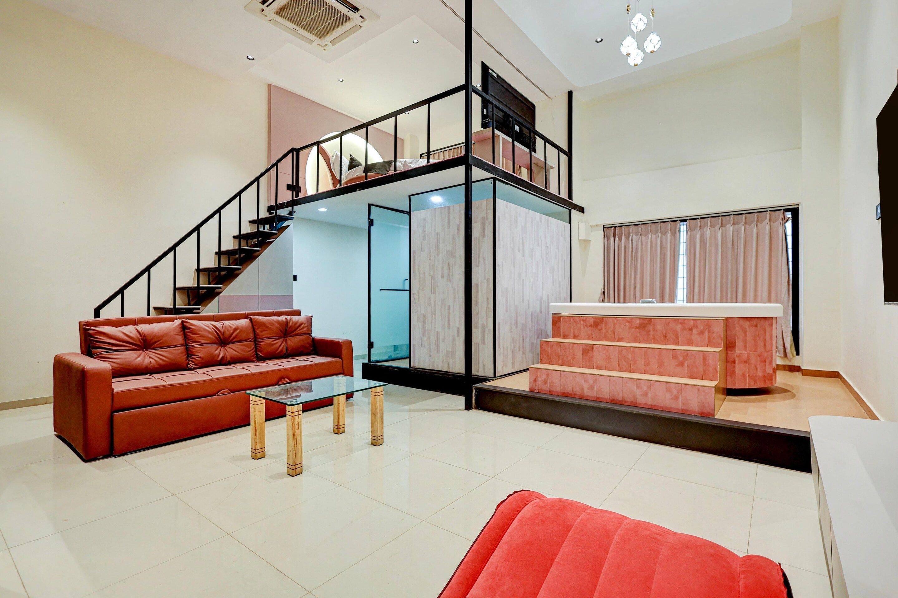 Una sala de estar moderna con una escalera, un sofá de cuero, una mesa de centro de vidrio y una butaca roja.