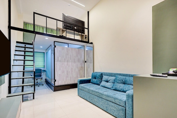 A modern interior with a loft-style bedroom, a sofa, and a desk area.