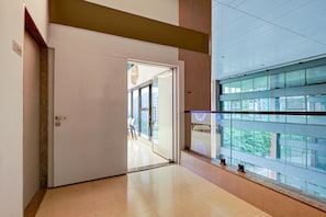 A corridor with a glass door leading to a room with a view of buildings.