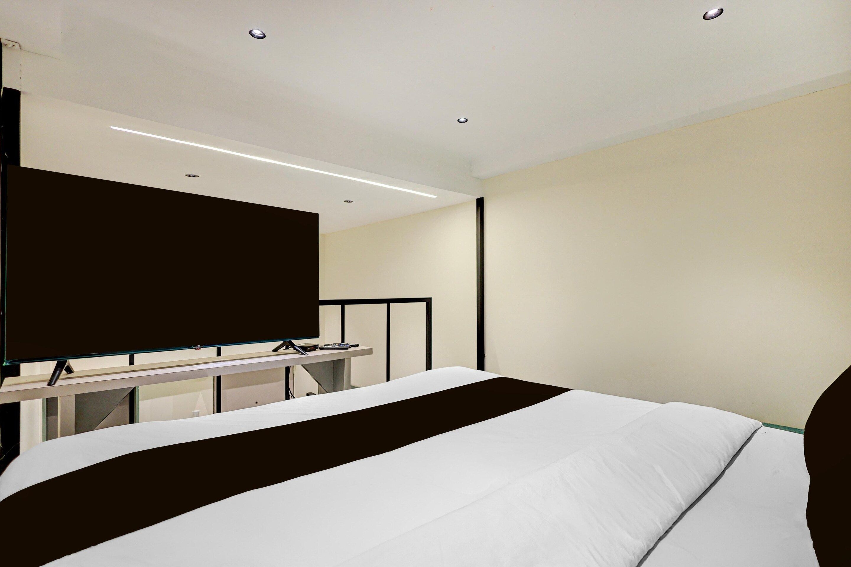 Quarto de hotel moderno com uma cama grande, televisão de tela plana e escrivaninha com computador.