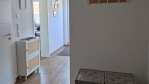 Un corridoio con pavimento in legno, una panca bianca, una mensola a parete e una porta che dà su un'altra stanza.