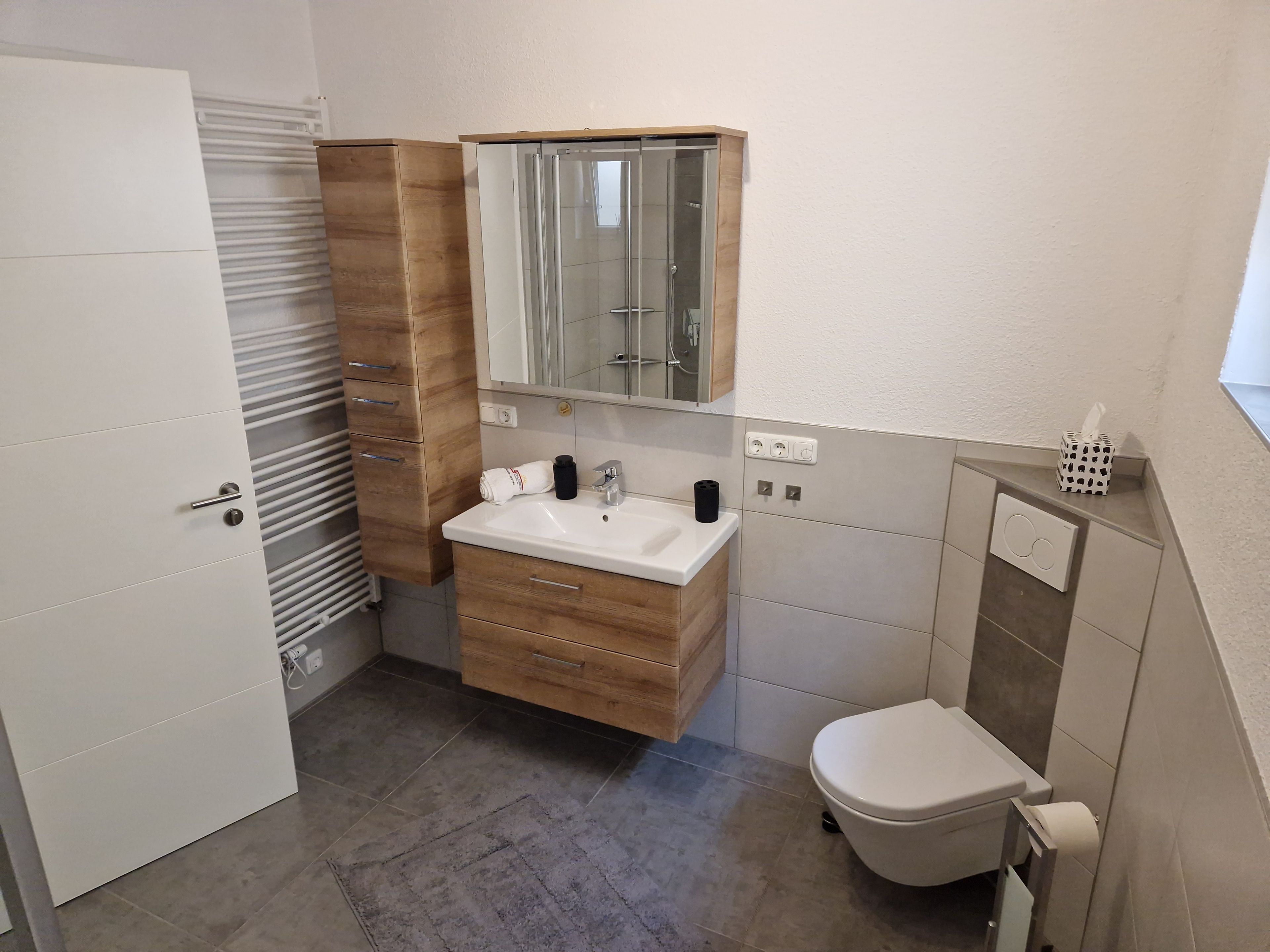 Ein Badezimmer mit Toilette, einem Holzbidet mit Spiegel, einem Waschbecken und einem Handtuch.
