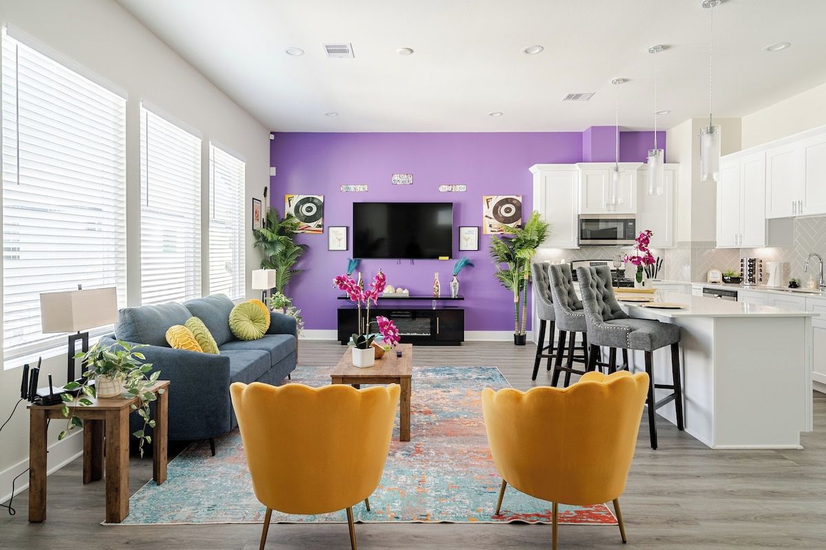 A modern living room with a sofa, chairs, a coffee table, and a TV.