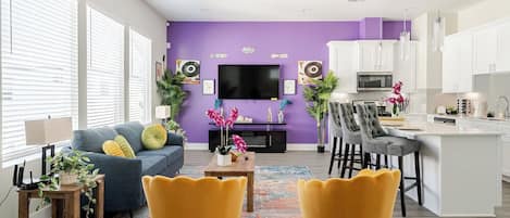 A modern living room with a sofa, chairs, a coffee table, and a TV.