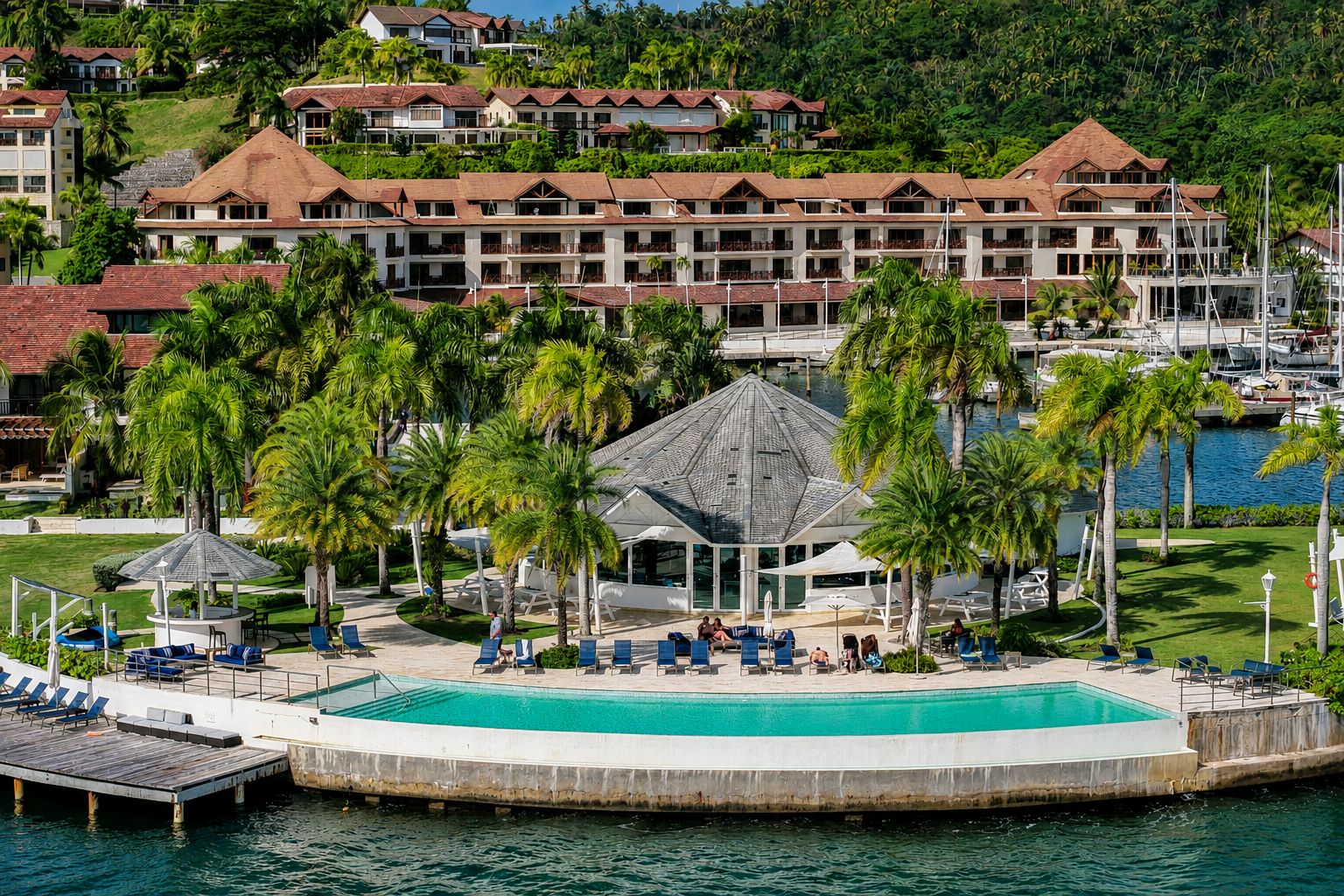 Un resort con una piscina grande, palmeras y vistas al agua.
