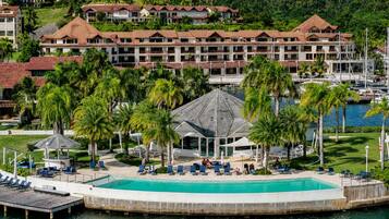 Un resort con una piscina grande, palmeras y vistas al agua.
