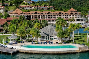 A resort with a large pool, palm trees, and a view of the water.