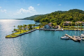 A marina with boats docked, a grassy area with palm trees, and a building with a white facade. - Apartment with Ocean View in Puerto Bahía w/ AC and fast WIFI (Doncel)