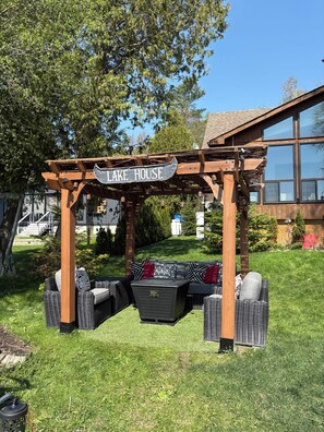 A wooden pergola with a sign reading 'LAKE HOUSE' above a seating area with wicker furniture. - As seen on season six of Scott’s vacation house rules on HGTV.  Lakeside Lodge! (Uxbridge)