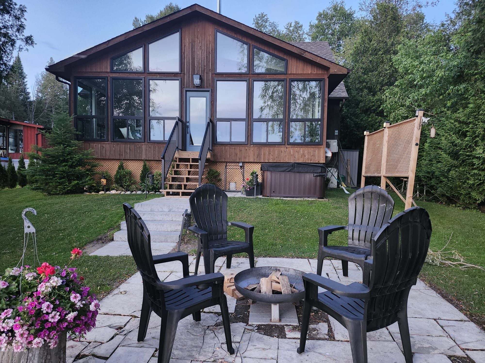 A wooden house with large windows, a deck, and outdoor seating.