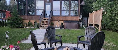 Una casa de madera con ventanas amplias, una terraza y mobiliario exterior.