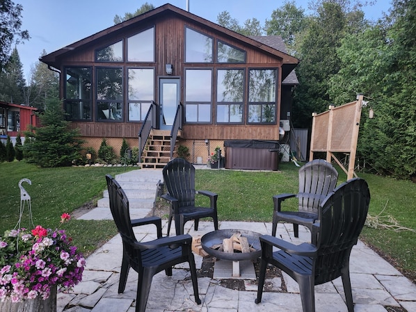 A wooden house with large windows, a deck, and outdoor seating.