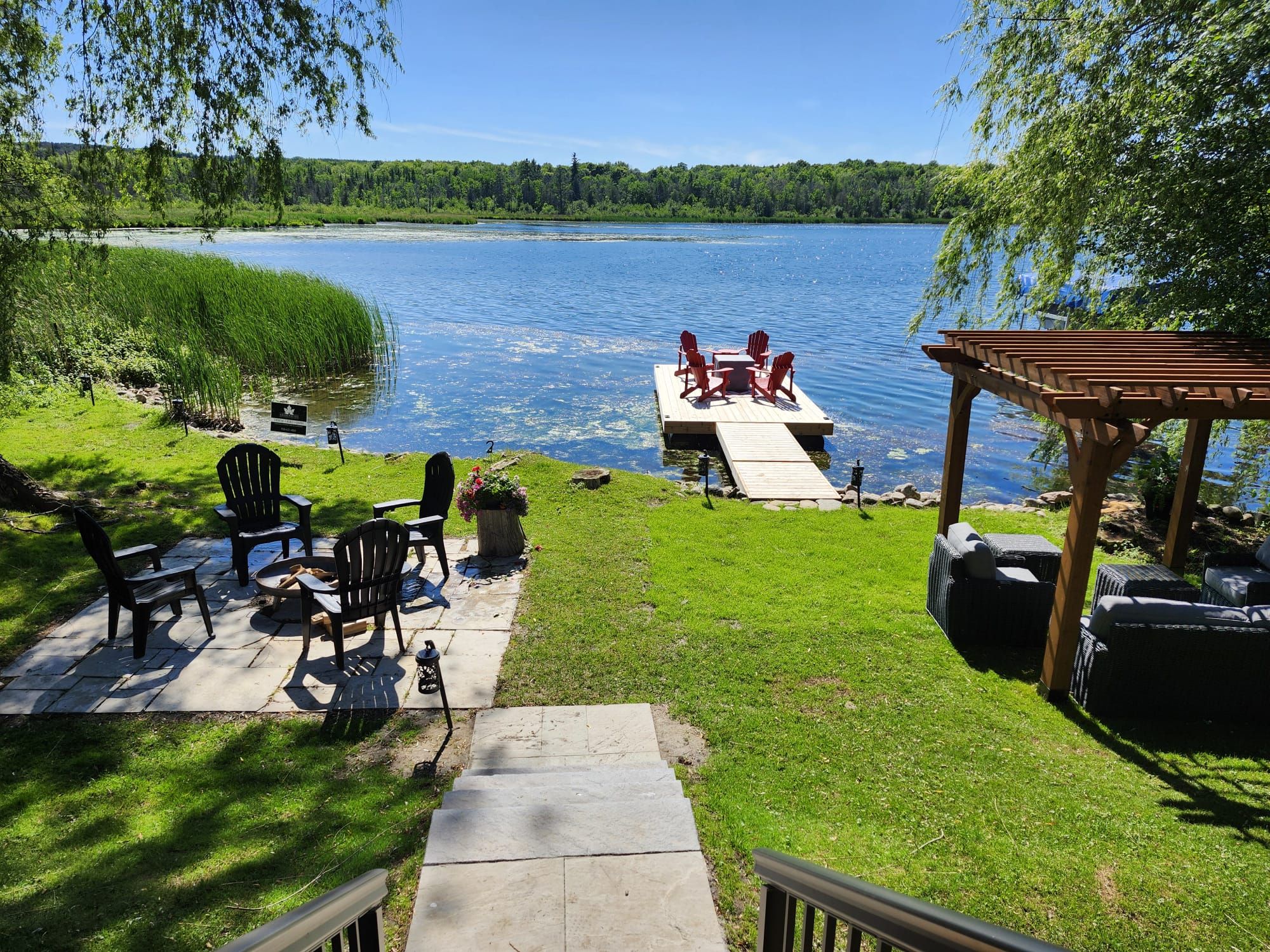 A lakeside patio with outdoor seating and a dock extending into the water.