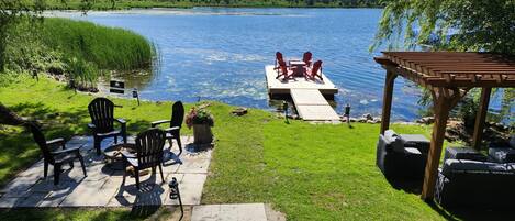 A lakeside patio with outdoor seating and a dock extending into the water.