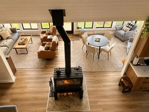A living room with a fireplace, sofas, a coffee table, and a dining area with chairs.