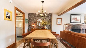 Un coin repas avec une table et des chaises en bois, un lustre et une cheminée.
