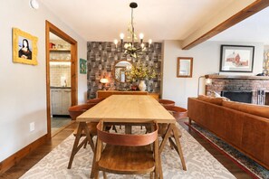 Een eetruimte met een houten tafel en stoelen, een kroonluchter en een open haard.