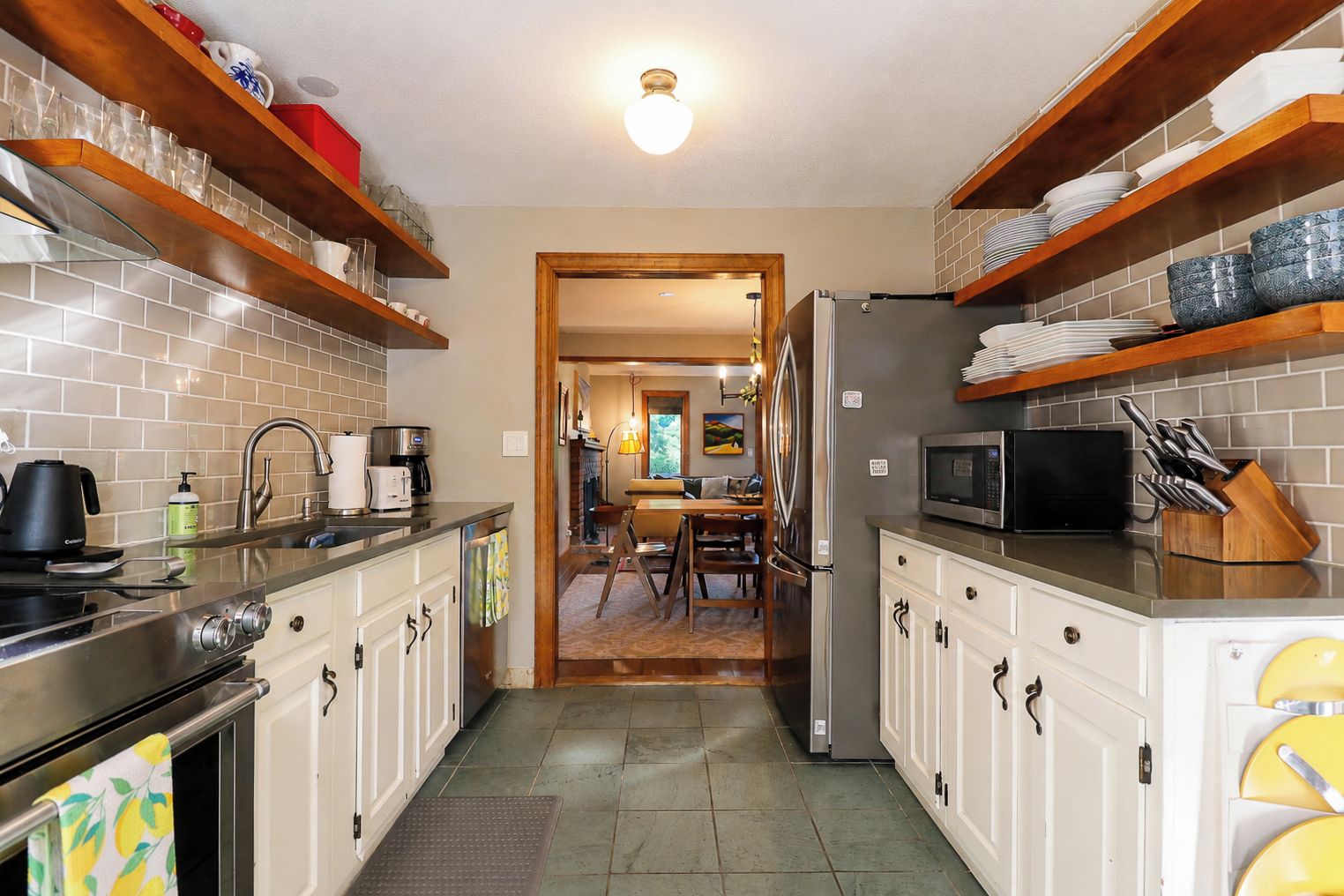 A kitchen with a stove, sink, and refrigerator, leading to a dining area with a table and chairs.