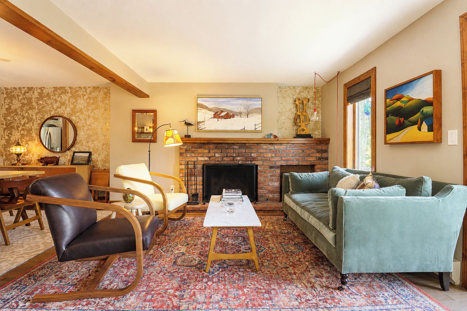 A living room with a fireplace, a sofa, a chair, a table, and a rug.