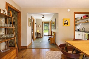 A kitchen with wooden shelves, a dining table, and a bench.