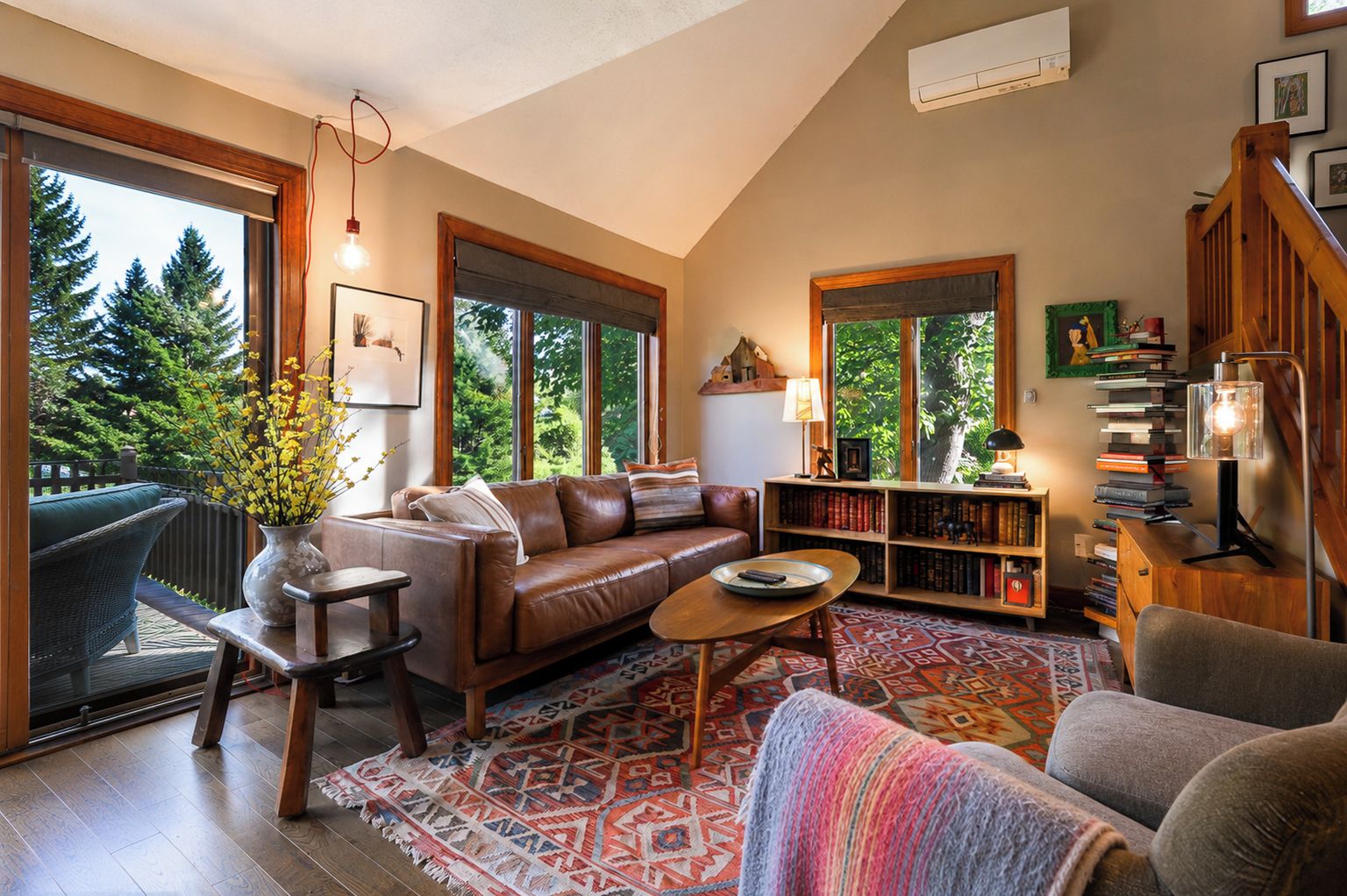 A cozy living room with a leather sofa, a coffee table, and a bookshelf filled with books.
